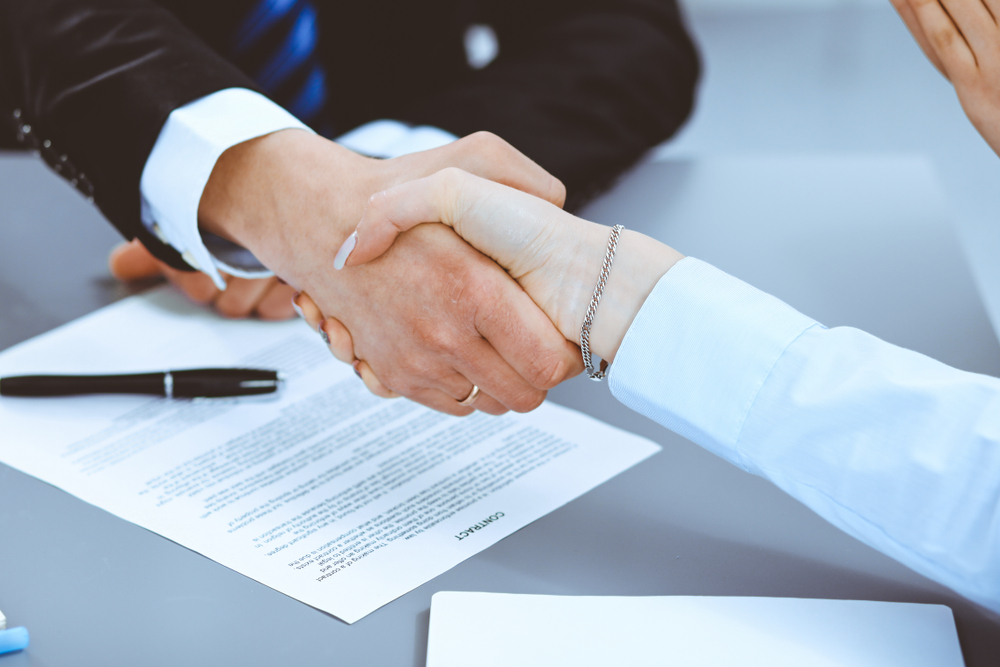  Business people shaking hands, finishing up a meeting over a translated legal document.